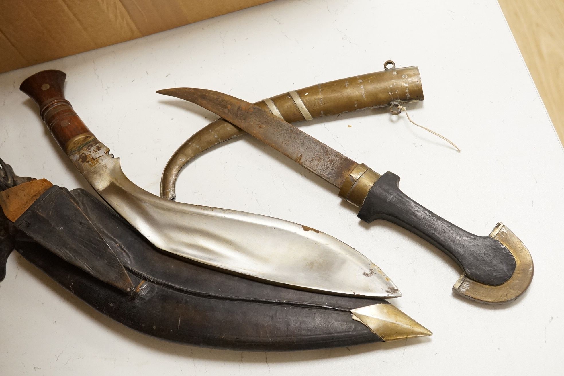 An Indian Kukri with brass mounted wooden handle its leather sheath, and a Moroccan Jambiya, together with a hardstone and wrought iron candle stand